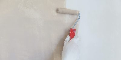 painter hand in white glove painting a wall with paint roller